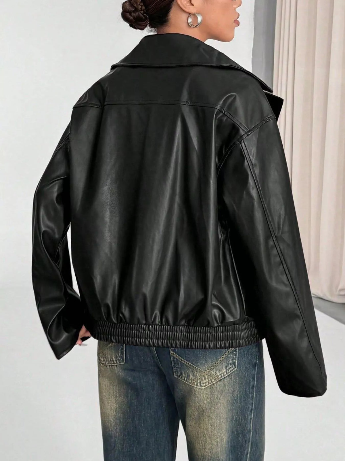 Rückansicht der oversized schwarzen Faux-Leder-Jacke mit glatter Rückseite, horizontaler Obernaht und elastisch gesammelten Bündchen.