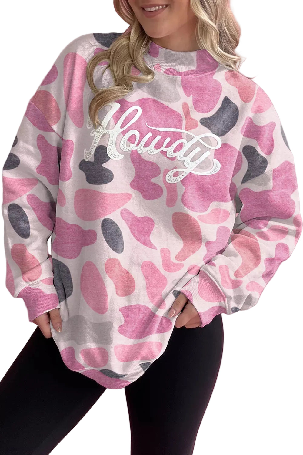 Model wearing pink grey abstract camo sweatshirt with white Howdy script and black leggings