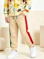 Beige Jogginghose mit roten und grünen Seitenstreifen, elastische Bündchen und Hand in der Tasche