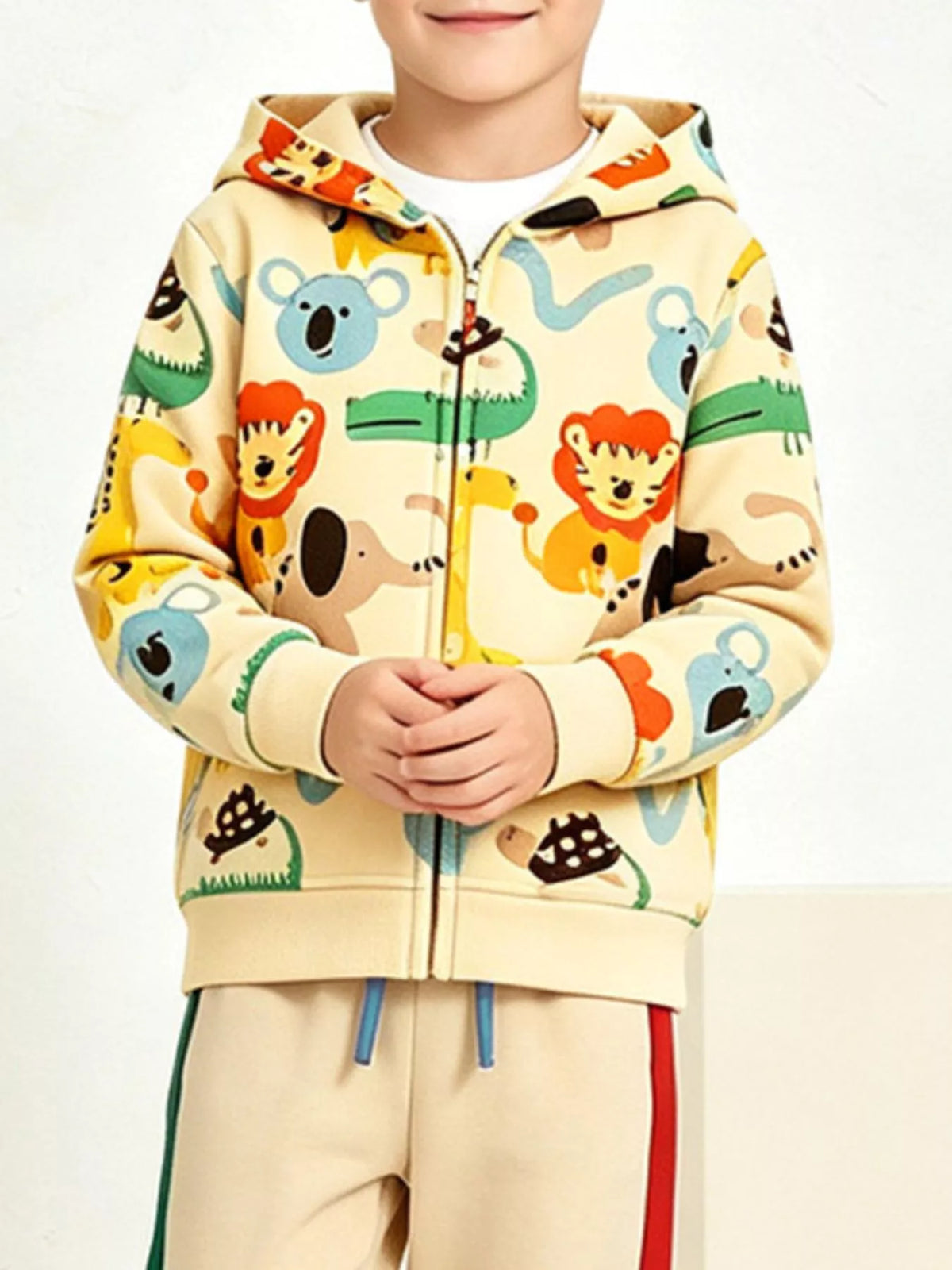 Nahaufnahme von leuchtend orangen Löwen und blauen Koalas auf beigem Hoodie, Hände gefaltet
