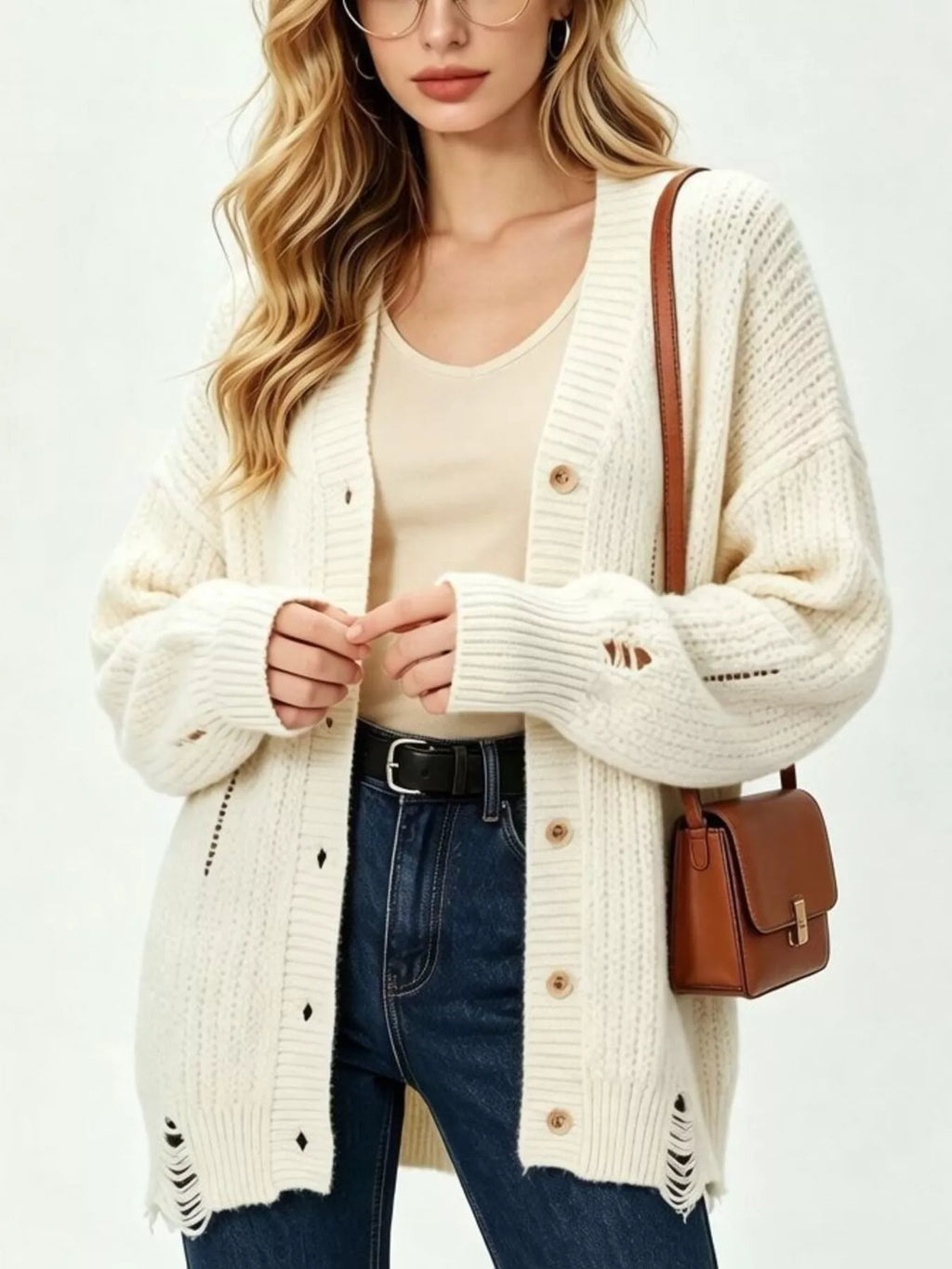 Nahaufnahme cremefarbener distressed Cardigan zeigt dicke Rippstricktextur und Diamantausschnitte