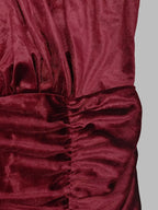 Détail du tissu velours bordeaux foncé avec fronces verticales créant un effet texturé sur fond gris