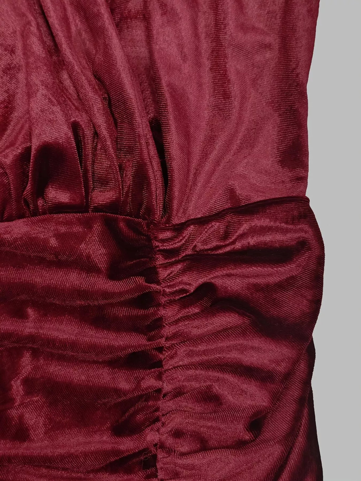Détail du tissu velours bordeaux foncé avec fronces verticales créant un effet texturé sur fond gris