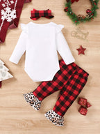Disposición plana completa del conjunto navideño de tres piezas para niña con body, pantalones a cuadros, diadema y guirnalda festiva
